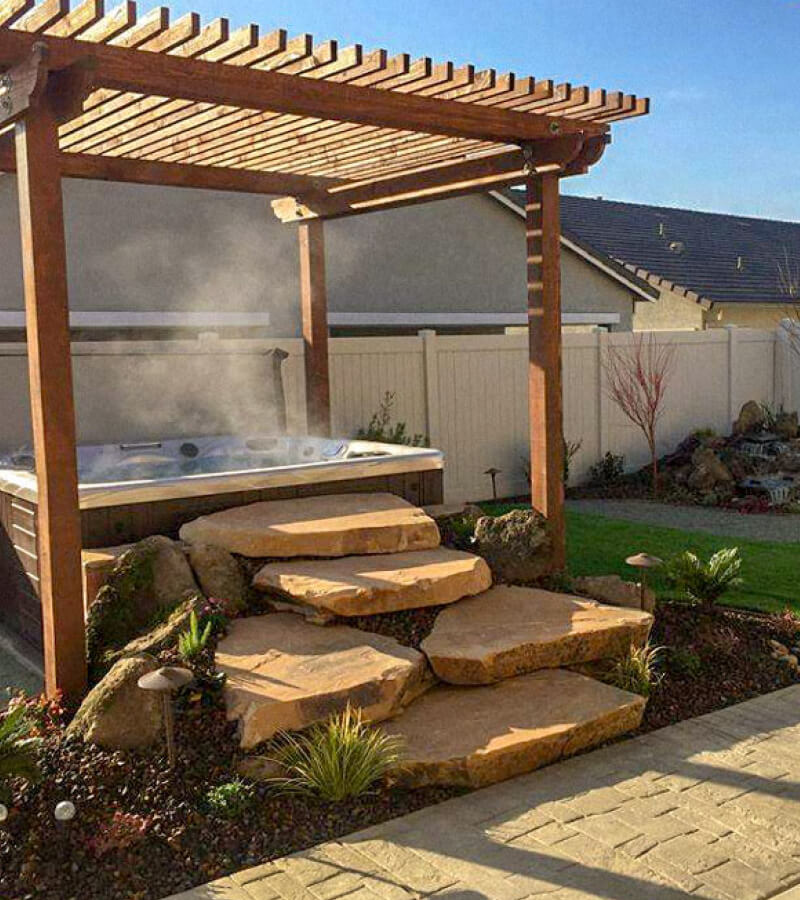 Zen-inspired hot tub patio with pergola and stone accents